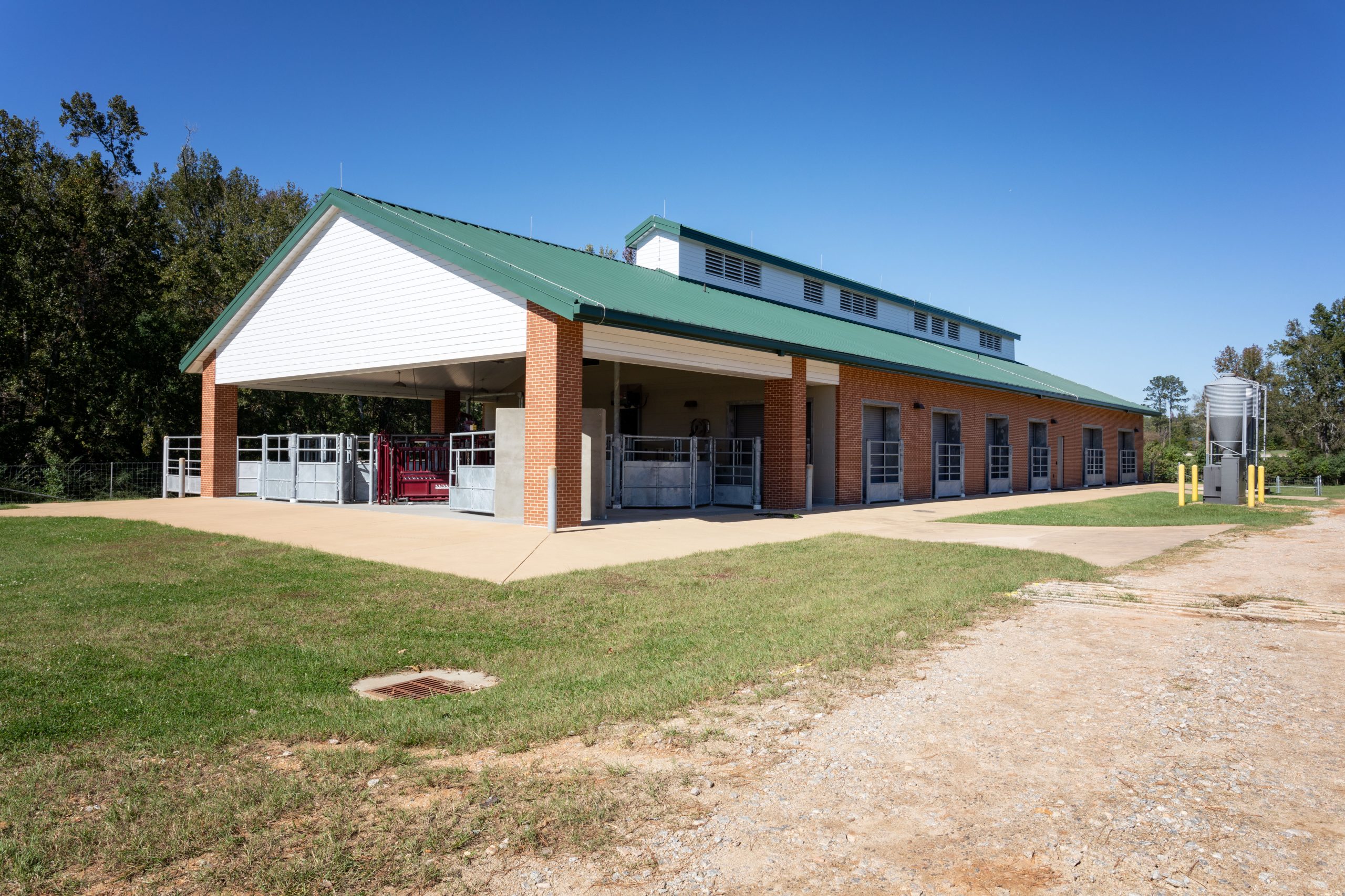 Red brick barn with green roof and silver grain silos